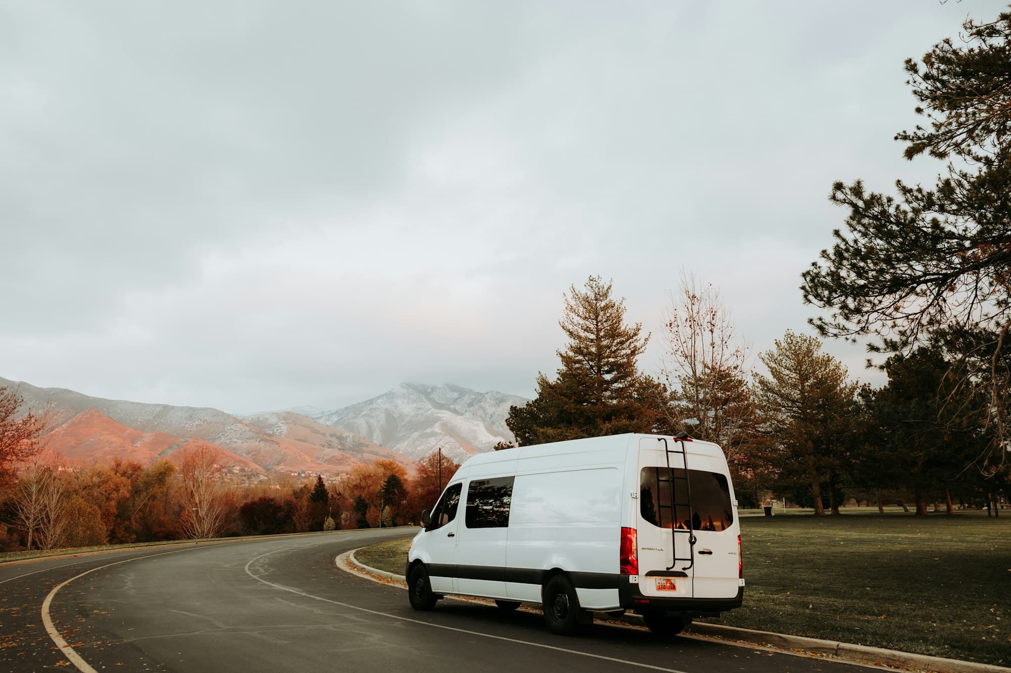 A camper van on a curving road through the mountains, headed north
